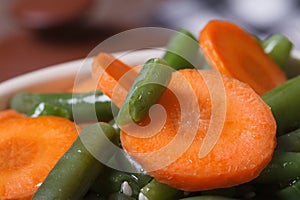 Macro chopped carrot slices and green beans in a bowl