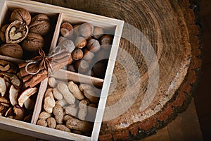 Macro cinnamon sticks tied lace and star anise with three kinds of nuts and dried fruits of apples in a box on a wooden background