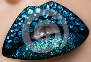 Macro and close-up creative make-up theme: beautiful female lips with black lipstick, blue diamonds and sequins, retouched photo