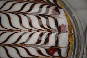Macro close up food image of a homemade Bakewell tart with white icing and a chocolate pattern topping with red fruit cherries