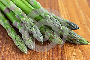 Macro close-up of green asparagus on used kitchen board, horizontally