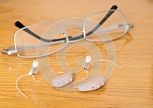 Close up of a pair of tiny modern hearing aid on bedside table photo