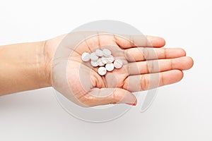 Macro Close up of medicinal or herbal pink white pill on female hand palm. Top view,