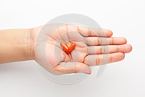 Macro Close up of medicinal or herbal red capsule on female hand palm. Top view,