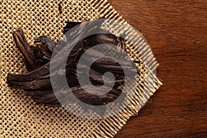 Macro close-up of Organic Alkanna tinctoria or ratan jot on the wooden top background and jute mat. Pile of Indian Aromatic Spice.