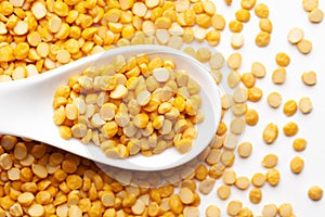 Macro Close-up of Organic Bengal Gram Cicer arietinum or split yellow chana dal on a white ceramic soup spoon. Top view, over