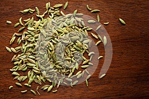 Macro close-up of Organic Fennel Seeds Foeniculum vulgare Badi sonf on wooden top background. Pile of Indian Aromatic Spice.