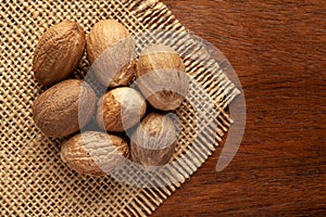 Macro close-up of Organic nutmeg seed  Myristica fragrans on the wooden top background and jute mat.