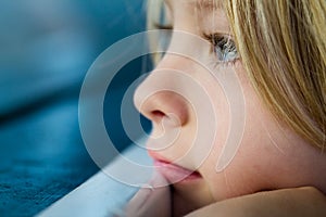 Macro close-up of sad child looking out of window