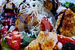 Macro close up of salad with fried turkey breast, tomatoes, green corn lettuce, fresh grated pecorino cheese and brown balsamic