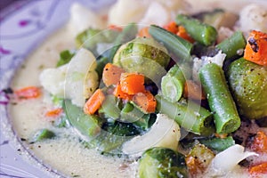 Macro close up shot of mixed vegetable soup in a bowl. Chopped carrot, green beans, cauliflower, brussels showing healthy home