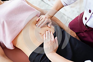 Macro close up of therapist hands doing visceral massage on female abdomen