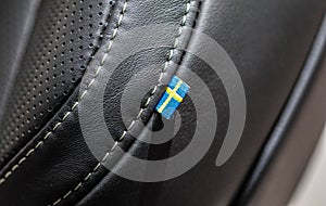 The macro close up view of Swedish flag on leather car seat.
