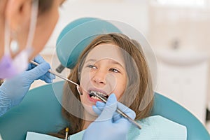 Macro close up of young child with open mouth at dentist. Teeth checkup at dentist's office. Dentist examining girls teeth in the