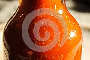 Macro closeup of isolated glass bottle with spicy hot red sauce, copy space for text