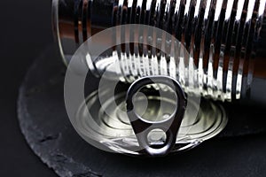 Macro closeup of isolated shiny metal food can with lid on black slate stone background