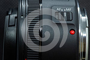 Macro closeup photo of lens to dslr camera on dark background view of red dot and silver extension ring and autofocus button
