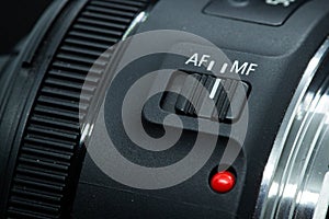 Macro closeup photo of lens to dslr camera on dark background view of red dot and silver extension ring and autofocus button