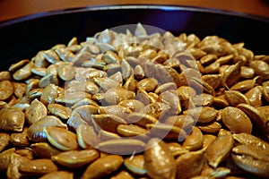 Macro closeup pumpkin seeds on black dish brown skin