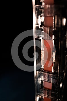 Macro Closeup of Red Tape on Bottom of Vertical Cassette Isolated on Black Background