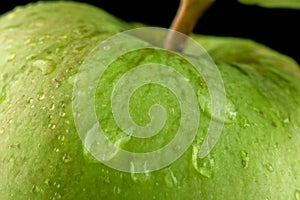 Macro closeup shot of drizzled green apple on black