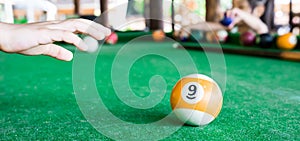 Macro closeup shot of a nine billiard ball with a hand trying to grab it