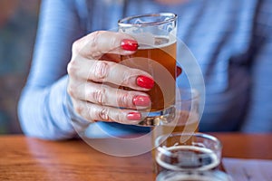 Macro closeup of woman holding a glass from beer flight