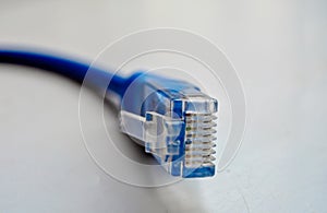 Macro cross section front angle view of blue RJ45 CAT6 shielded network data internet cable connector on gray, copyspace