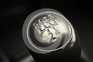 Macro detail of a black knob of a used manual shift gear (gear stick) in the aged vehicle