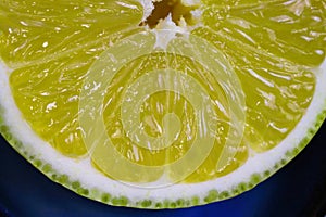 Macro detail closeup of yellow slice citrus fruit pulp with juice sacs, segment walls and white rind