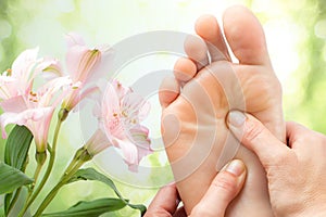 Macro detail of foot massage next to flowers.