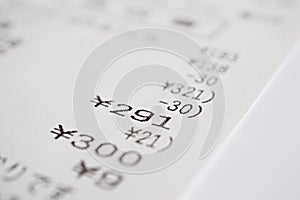 Macro detail of a Japanese paper receipt (white paper bill, sales slip) with a sum of several items