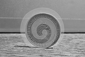 Macro detail of a silver and golden coin with head of queen in a value of two British Pounds 2 GBP on the wooden surface