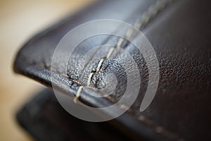 Macro detail of a white thread stitching black and brown stitched leather wallet