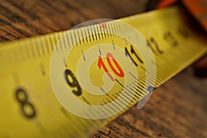 Macro detail of yellow metal tape meter with red and black numbers measuring length in centimeters