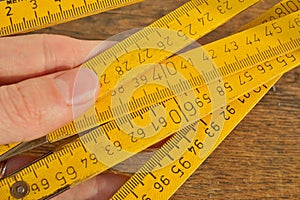 Macro detail of yellow metal tape meter with red and black numbers measuring length in centimeters