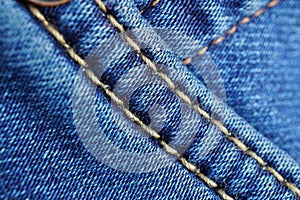 Macro detail of a yellow thread stitching typical blue men`s jeans