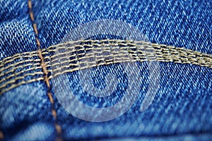 Macro detail of a yellow thread stitching typical blue men`s jeans