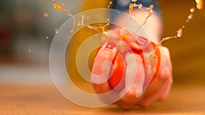 MACRO, DOF: Organic tomato explodes in a female chef\'s hand as she squeezes it.