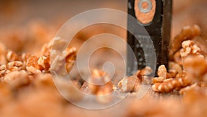 MACRO, DOF: Unrecognizable person crushes peeled walnut kernels with a hammer.