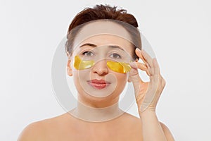 Macro female face. Beauty portrait of middle age woman with wrinkles and a gold patch under eye isolated on white background.