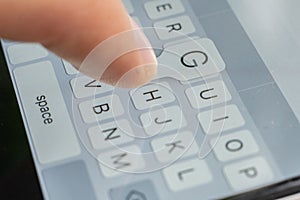 a macro of a finger typing text on the touch screen keyboard of mobile device