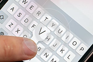 A macro of a finger typing text on the touch screen keyboard of mobile device