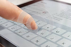 a macro of a finger typing text on the touch screen keyboard of mobile device