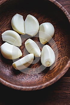 Macro food photography of peeled garlic cloves in a wooden bowl