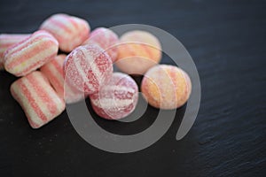 Macro food photography of sugar candy sweets in red pink and white stripe patterns on dark slate background