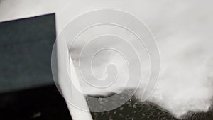 Macro of grains reflected off stone during circular saw cuts dark granite block.