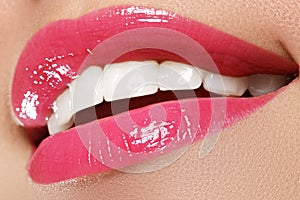 Macro happy woman's smile with healthy white teeth, bright pink