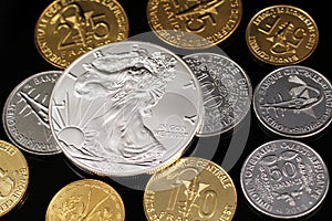A close up image of West African Franc coins and a silver American one ounce coin on a black background