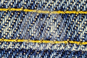 Macro image of blue jeans interwoven gold thread, denim texture background.